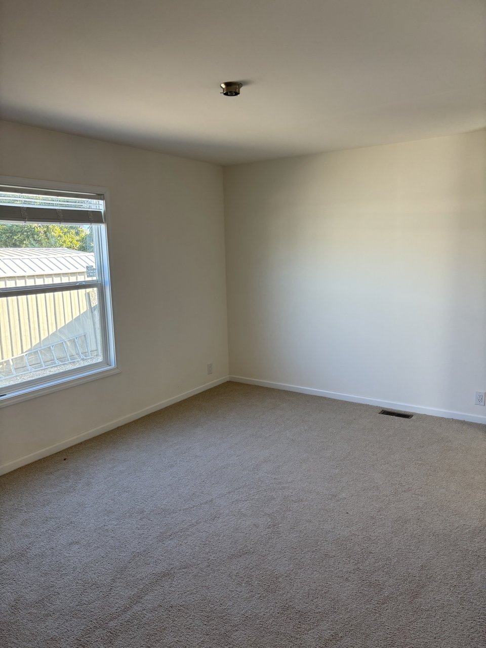 Carpeted bedroom with a window and ceiling fan